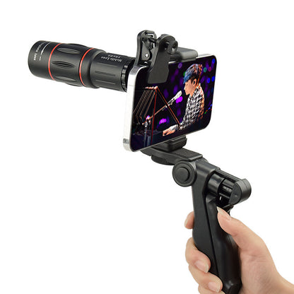 Main tenant un smartphone avec objectif 18x et poignée pistolet lors d'un concert